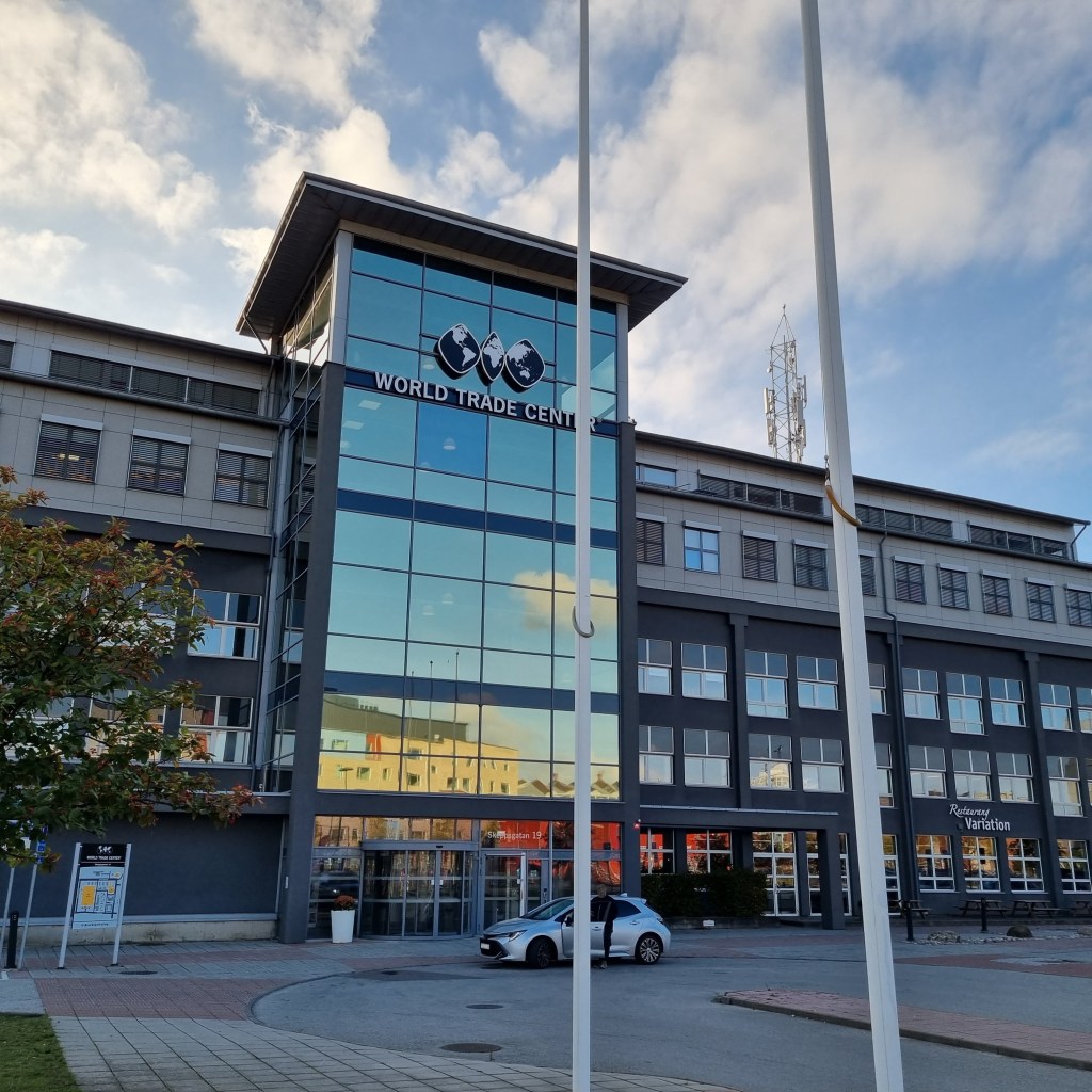 Glasfasaden till kontorshuset som speglar en himmel i solnedgång med blå och rosa nyanser